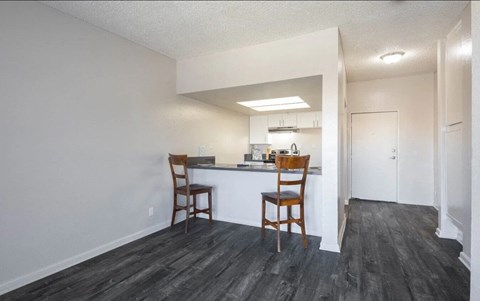 a kitchen with a bar and a living room with chairs
